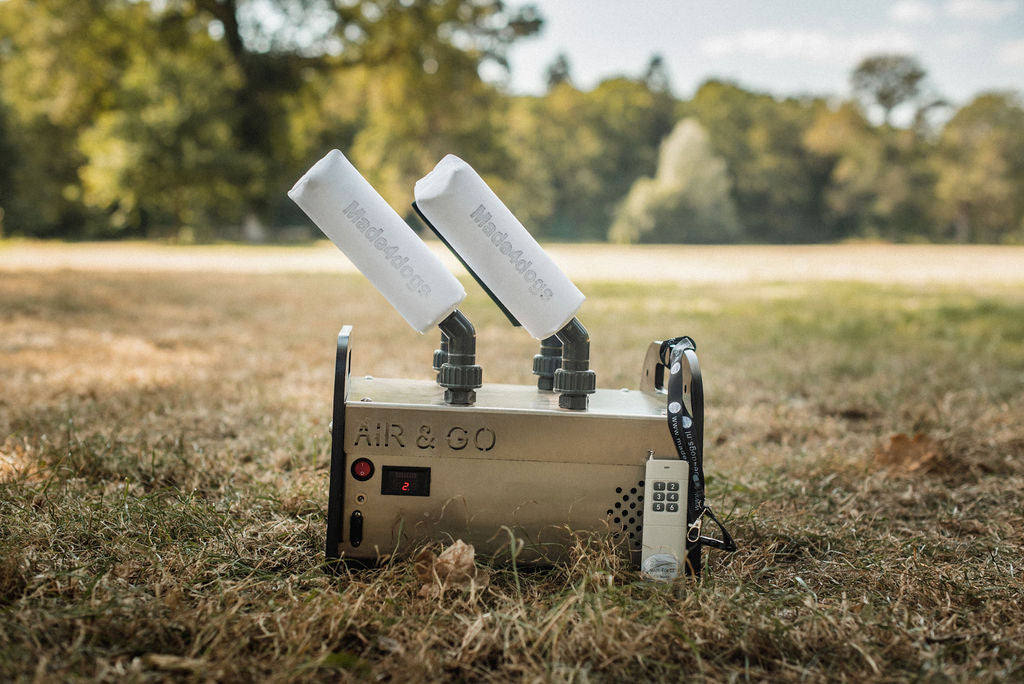 4-Shooter, der air&go Dummylauncher von made4dogs steht in der Natur auf einer Wiese, Bäume im Hintergrund