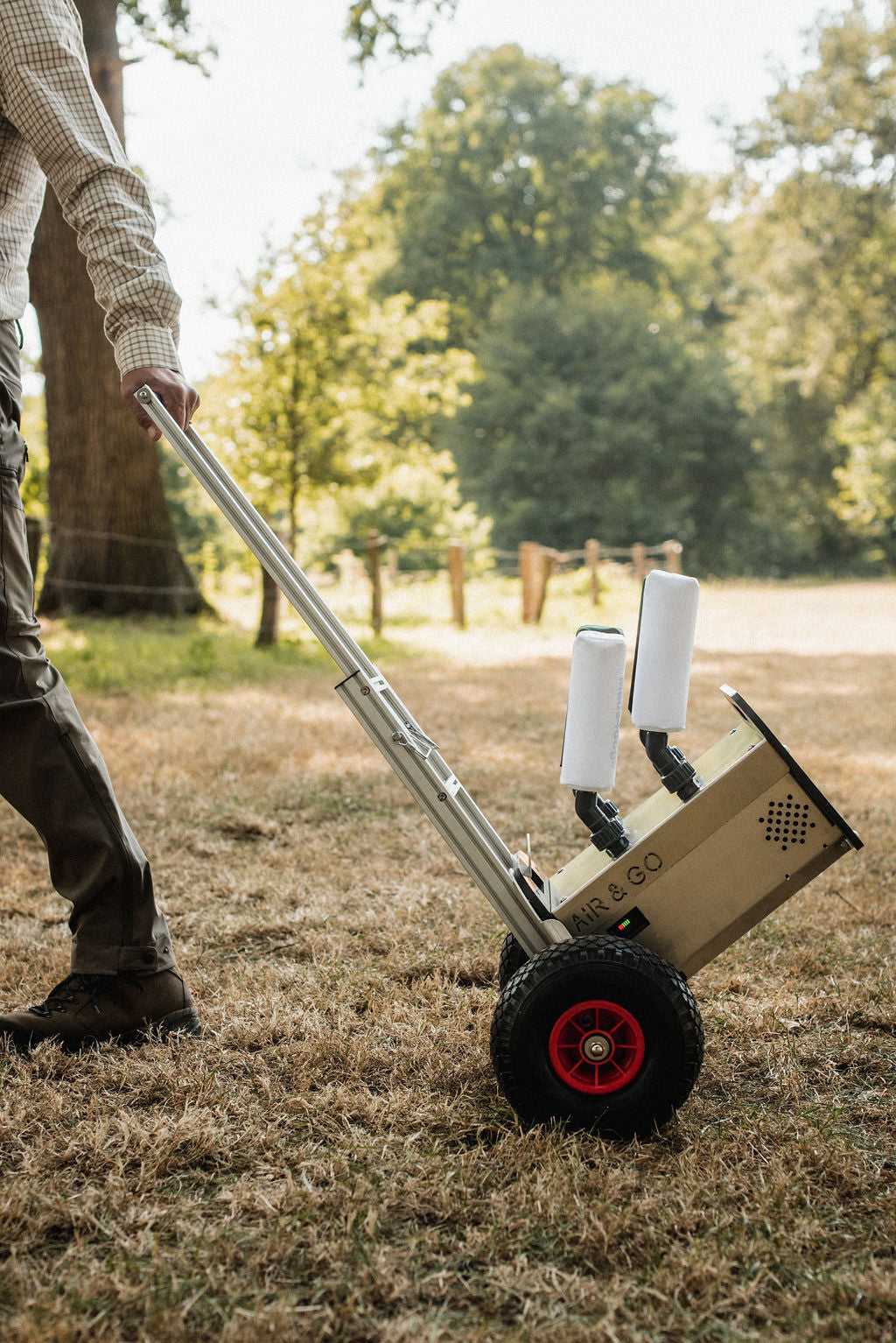 Ein Mann zieht seinen Air&GO Dummylauncher mit der Ride&GO Transporthilfe durch ein Gelände